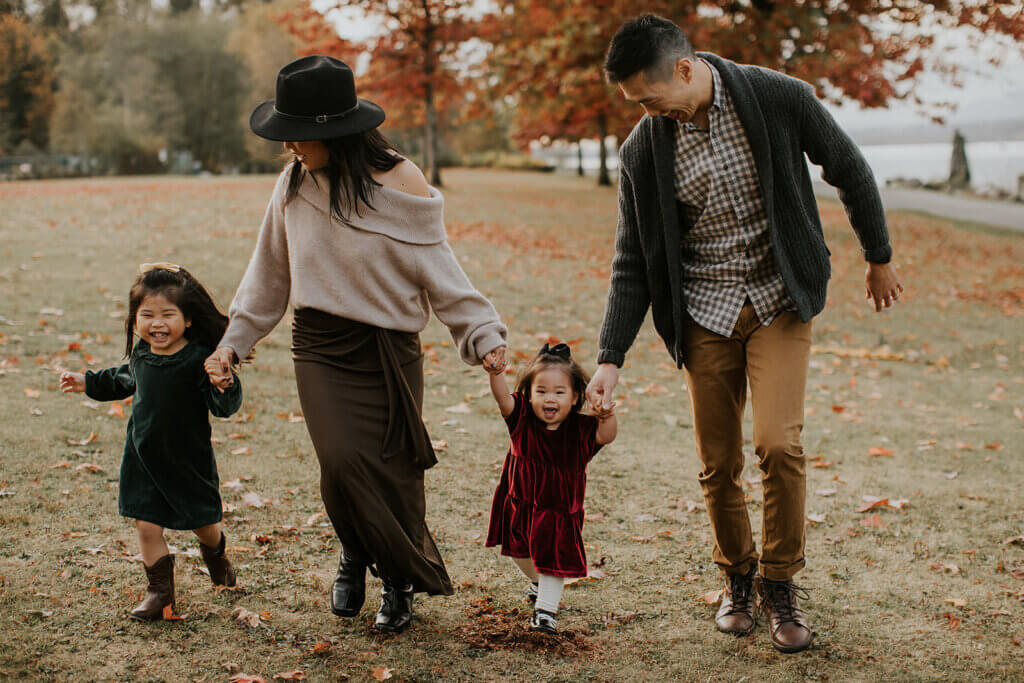 a family of four run through a field of fall leaves