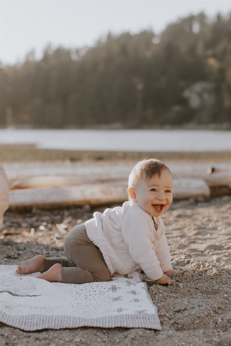 a ten month old boy crawling and smiling at the beach