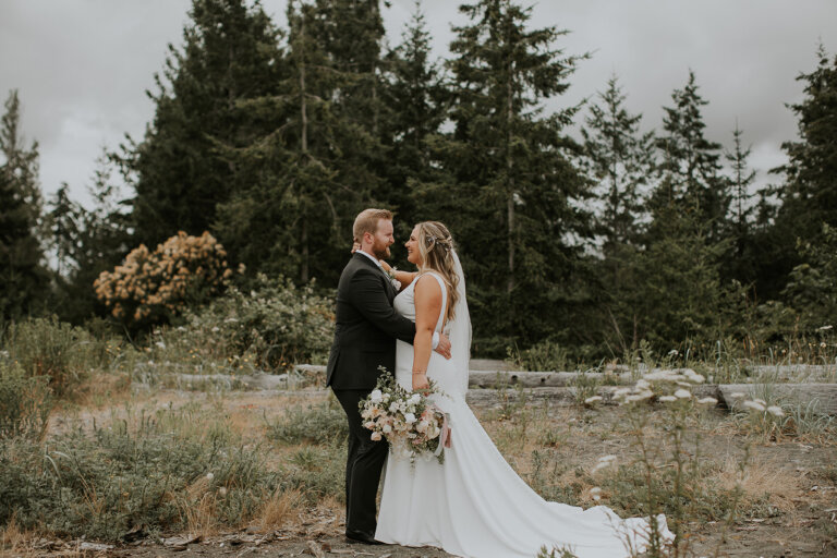 a bride and groom stand on a beach in Campbell River