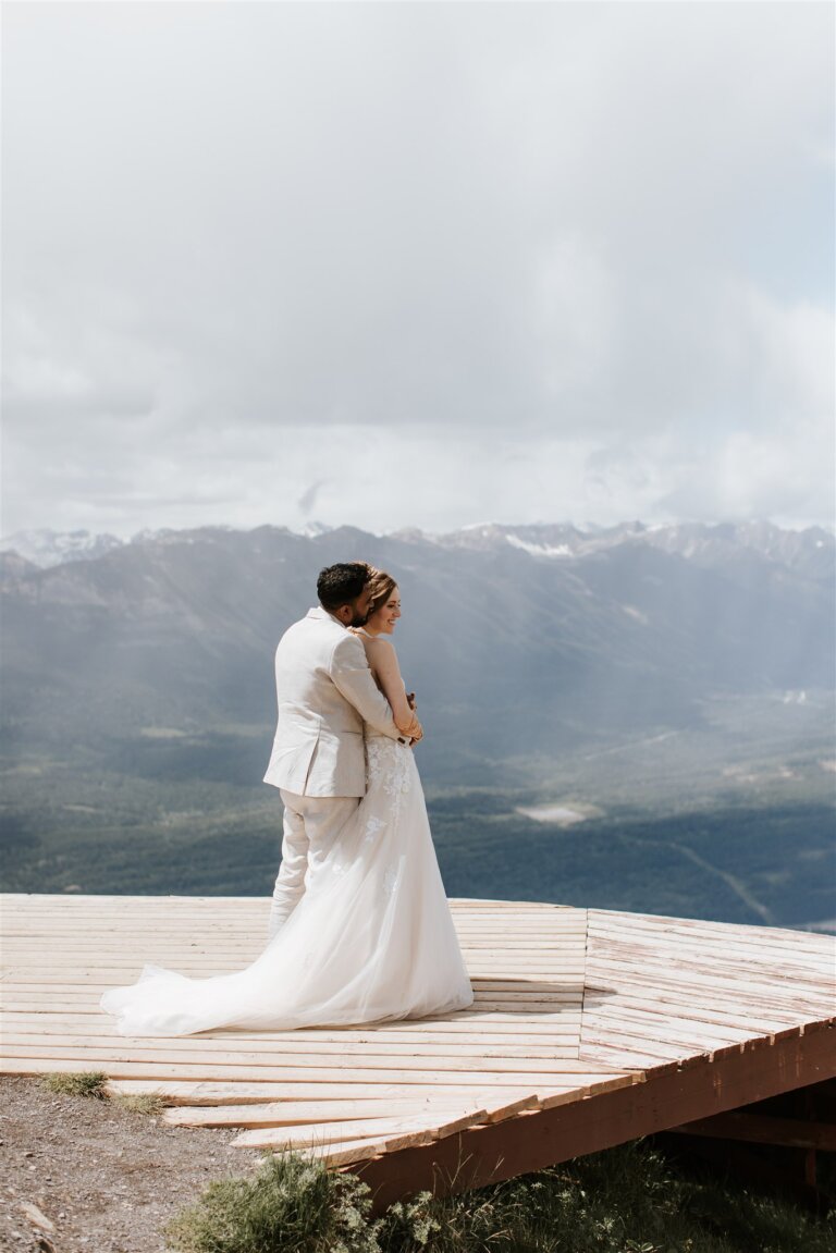 Couple embracing during mountain wedding portraits at Mount 7 in Golden, BC with sweeping mountain views