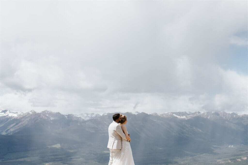 Couple embracing during mountain wedding portraits at Mount 7 in Golden, BC with sweeping mountain views