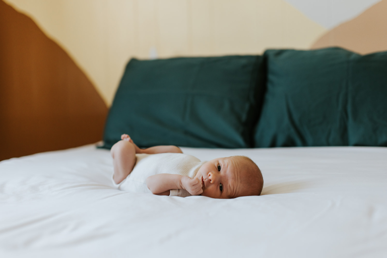 Newborn baby lying on a bed during an in-home lifestyle newborn session in Kimberley, BC