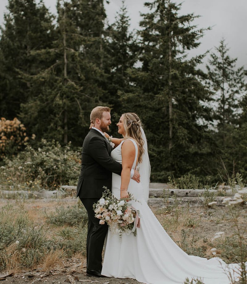 a bride and groom stand on a beach in Campbell River