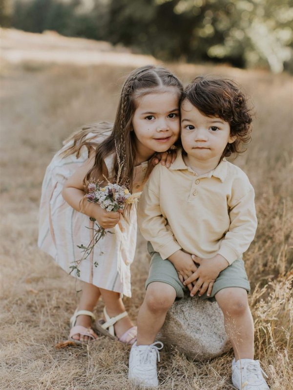 a brother and sister sit and smile at the camera