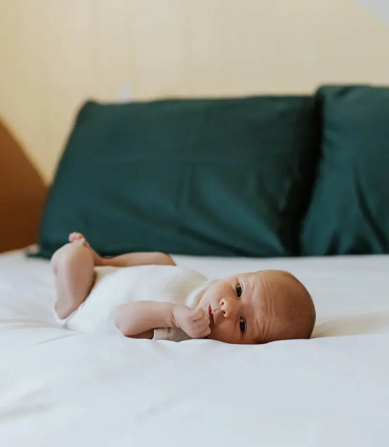 Newborn baby lying on a bed during an in-home lifestyle newborn session in Kimberley, BC