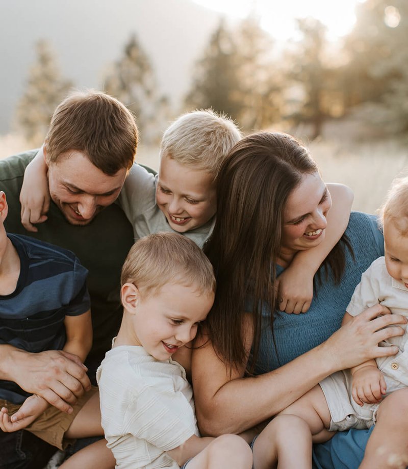 a family with four young boys laughing in a field near Kimberley, BC